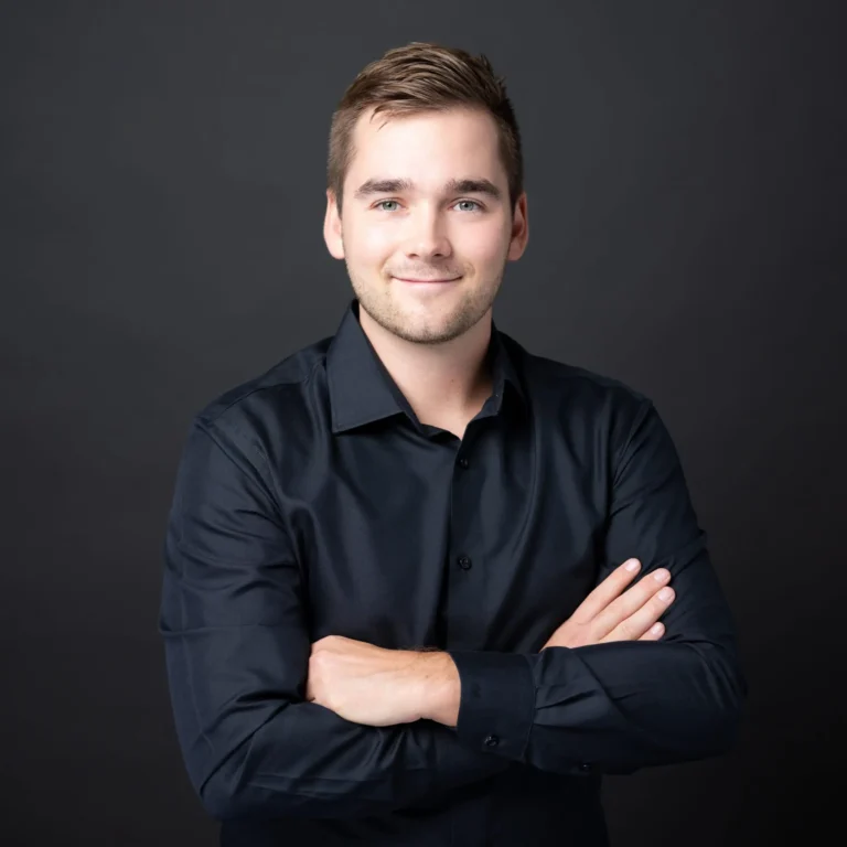 Portrait of E-Comsult founder Samuel Schweizer wearing a black shirt against a dark background.